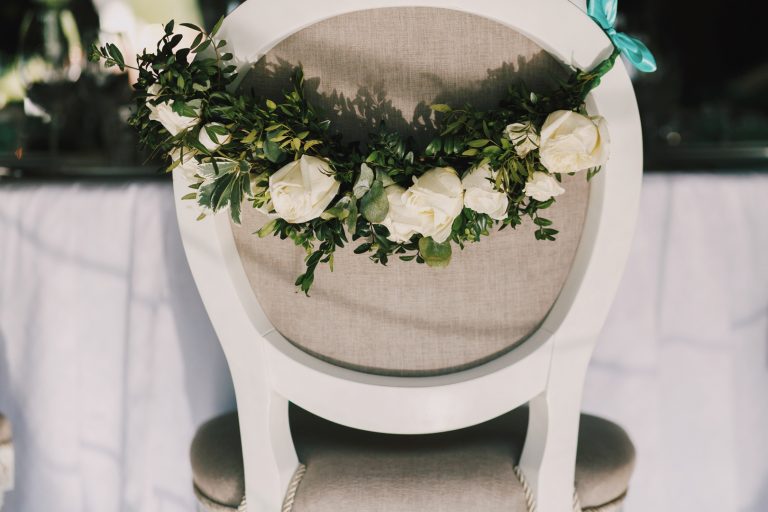 Garland of beautiful white roses hangs on the back of grey chair